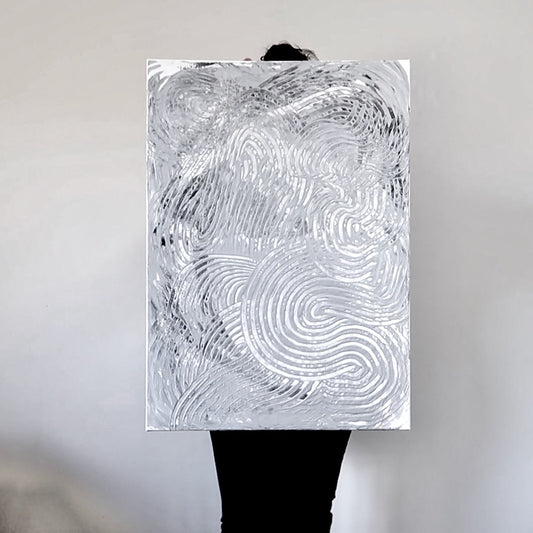 A person holding an abstract acrylic landscape painting with curved lines in black and white.