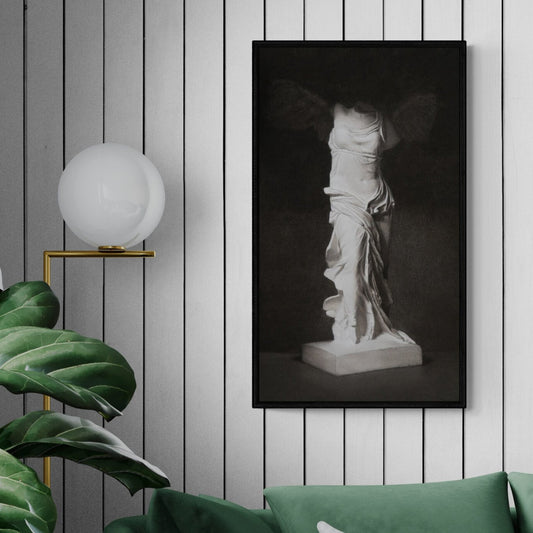 A charcoal drawing of the goddess Nike displayed in a home setting with a plant and lamp.